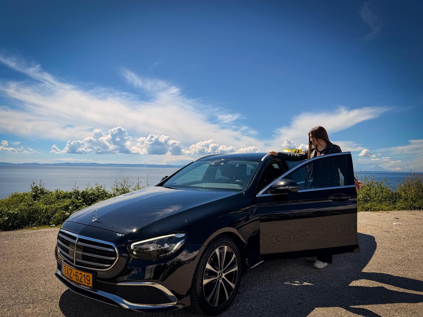 Passenger stepping into the Eagle Taxi Mercedes by the sea